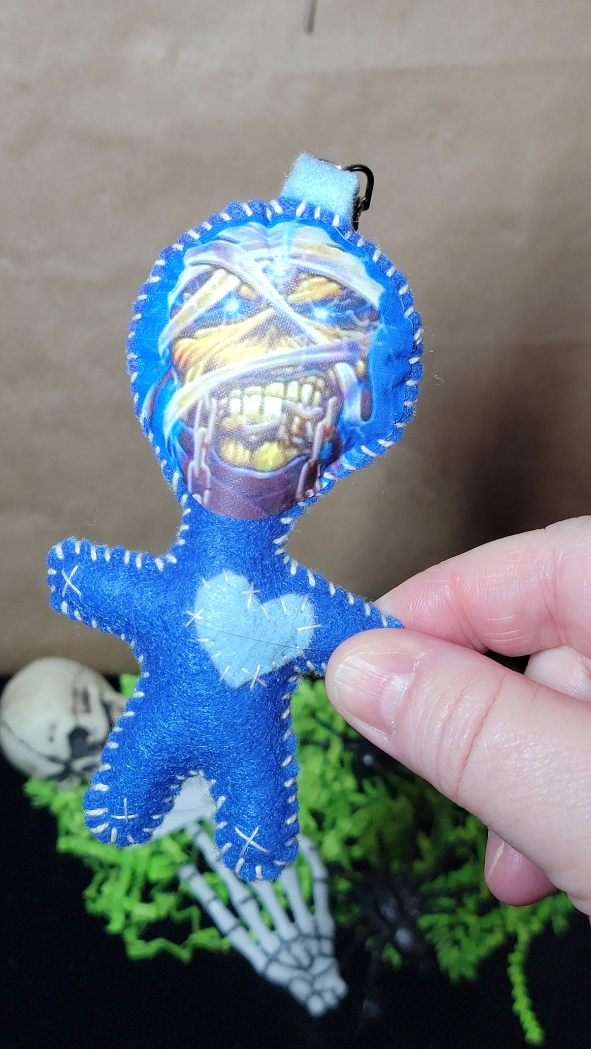 Close-up of handmade blue mummy Rock Mascot Stitchling showing its wrapped monster face and pale blue stitched heart⠋