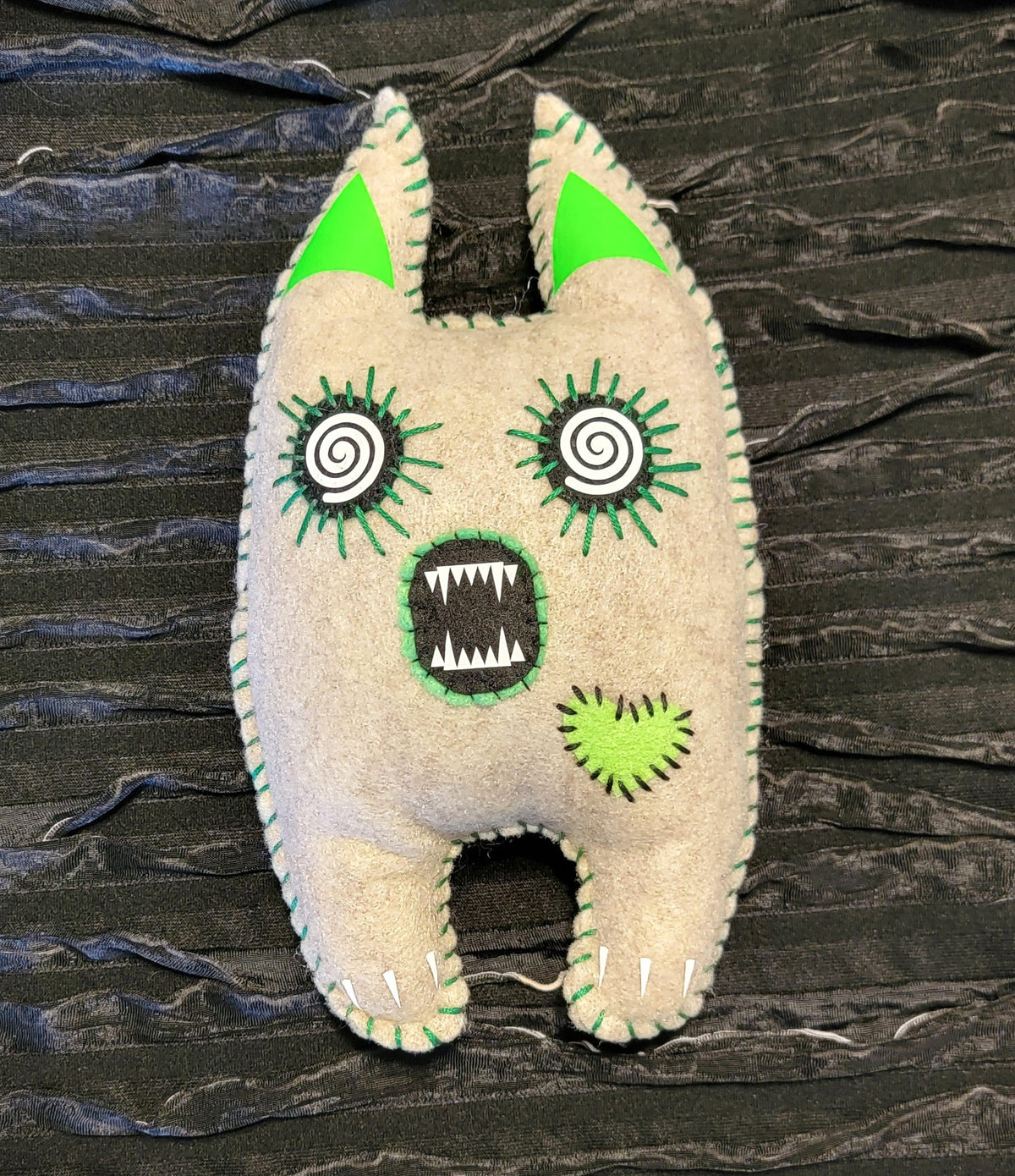 Stuffed toy with a monster design on a textured black background