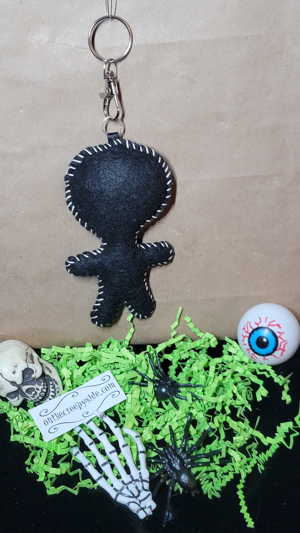 Back view of handmade black felt Mini Music Mascot Aviator Eddie Stitchling keychain with white hand-stitched edging