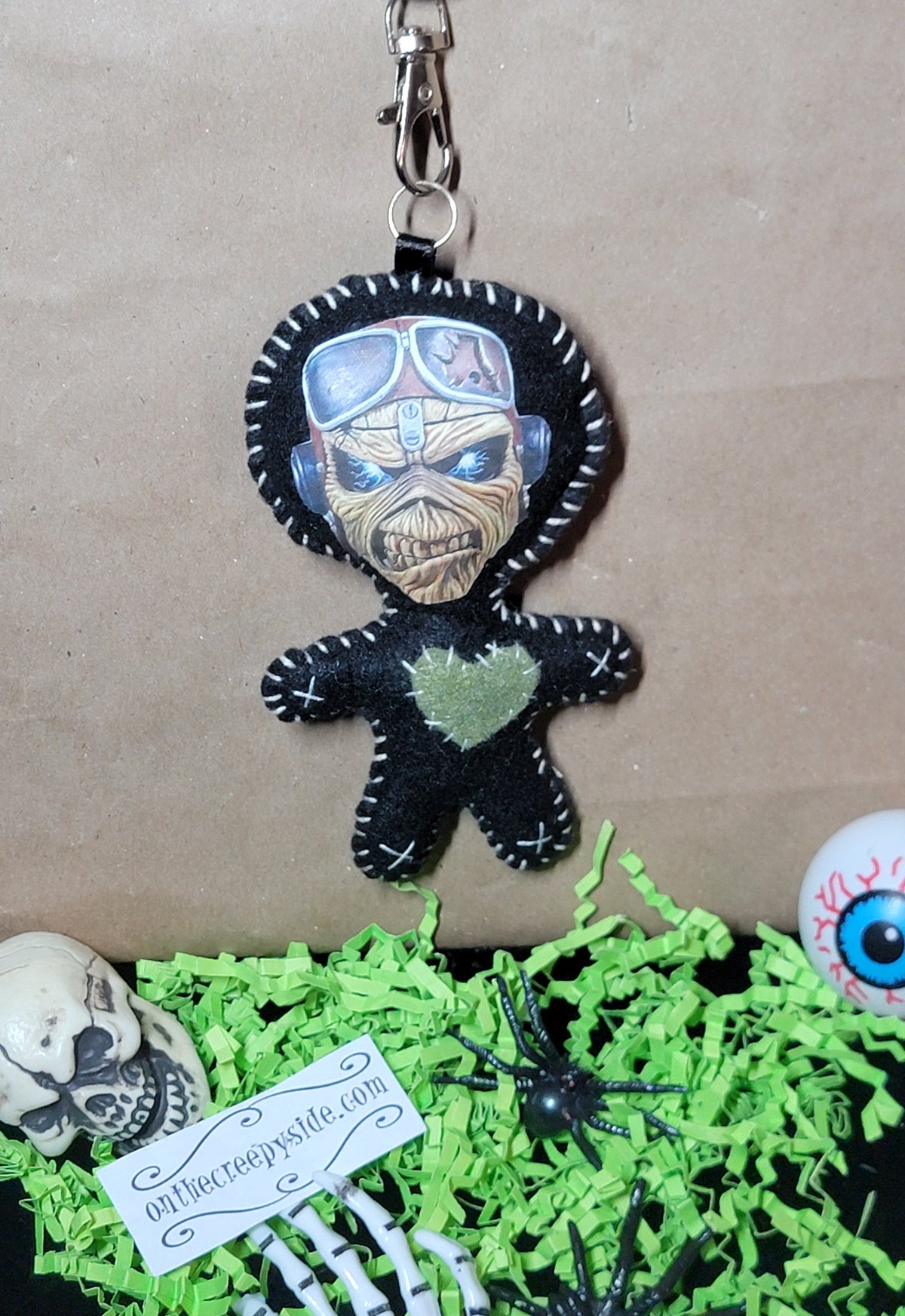 Front view of handmade black felt Aviator Eddie Stitchling keychain with goggles, white stitching, and green heart