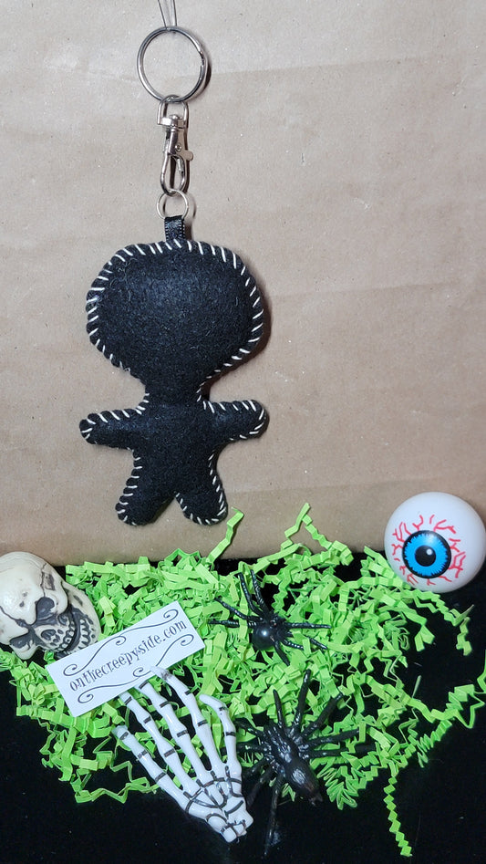 Back view of handmade black felt Mini Music Mascot Eddie Stitchling keychain showing white hand-stitched edging