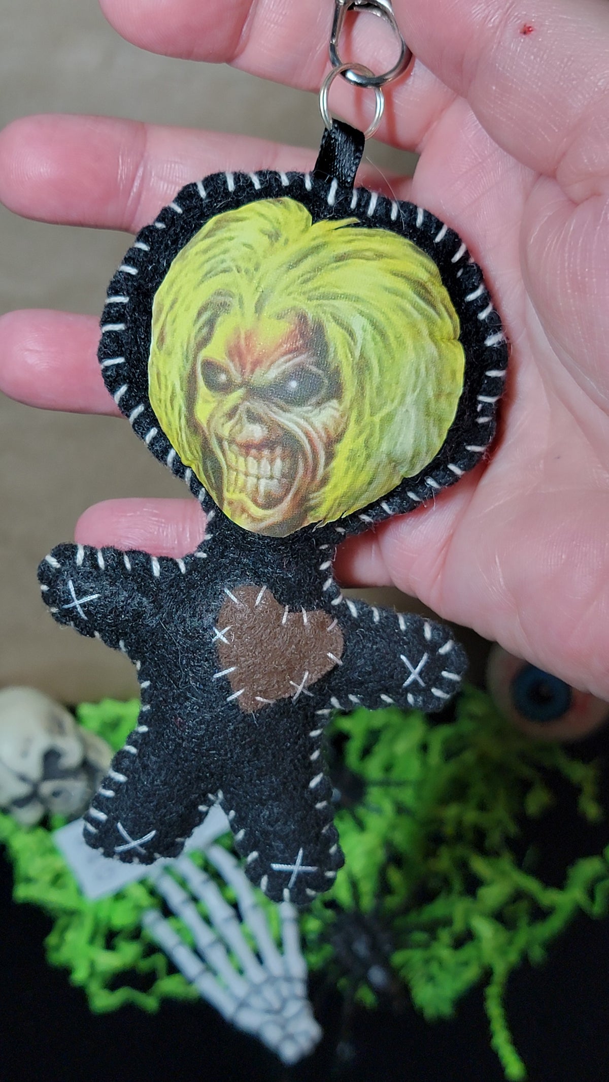 Close-up of handmade Mini Music Mascot Eddie Stitchling felt keychain with button-eyed monster face and white stitching
