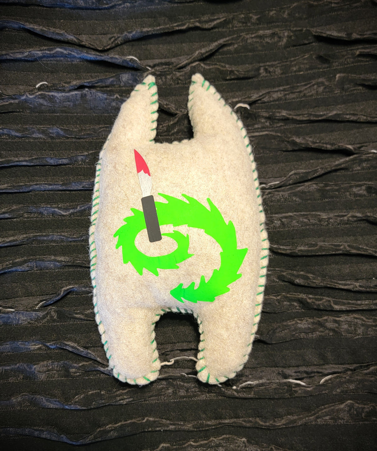 Plush toy with a green design on a textured dark background