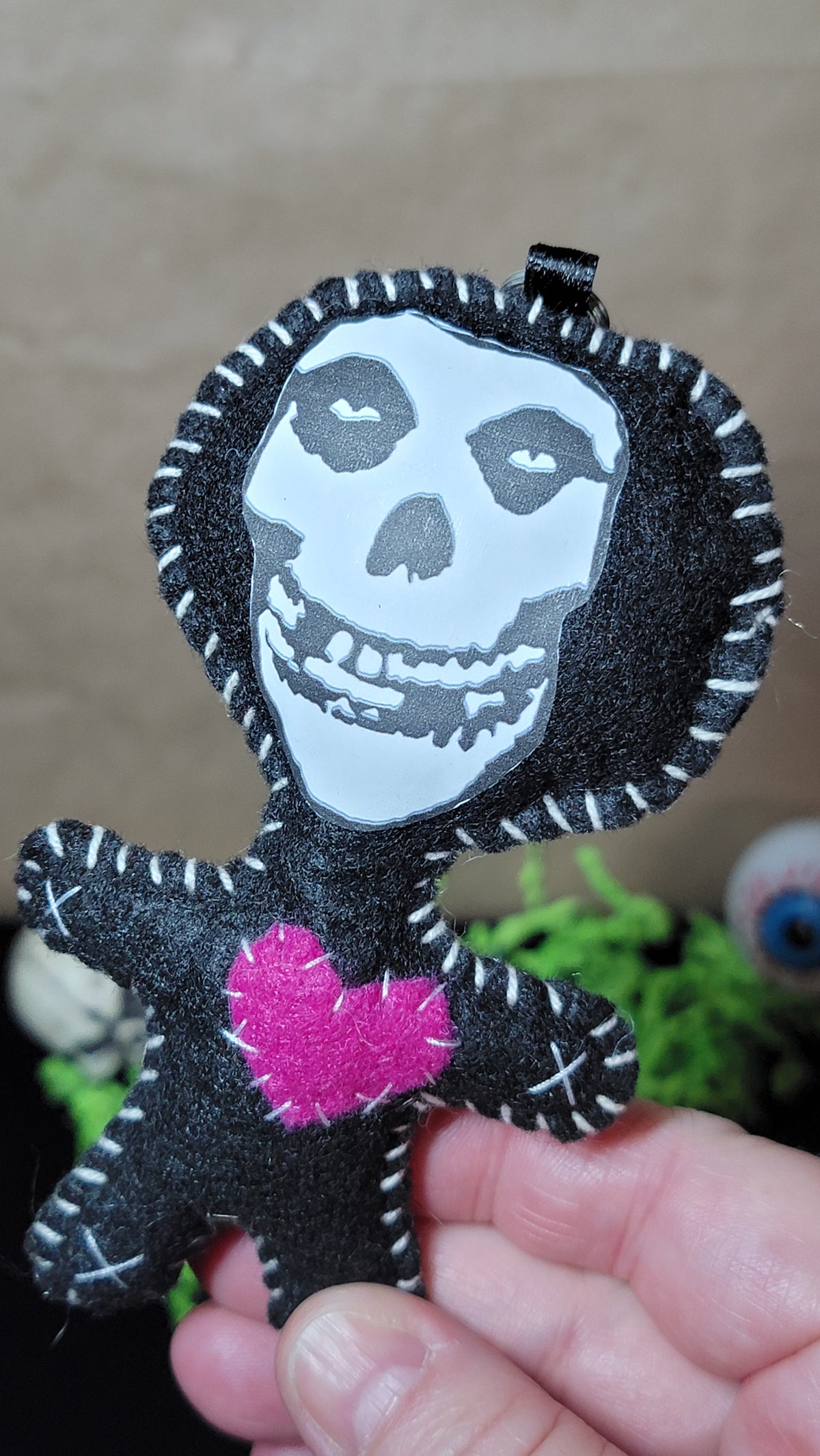 Close-up of handmade punk rock skull Stitchling showing its black-and-white skull face, white stitching, and hot pink heart